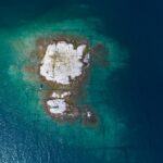 Aerial drone view of a remote rocky island in open sea.